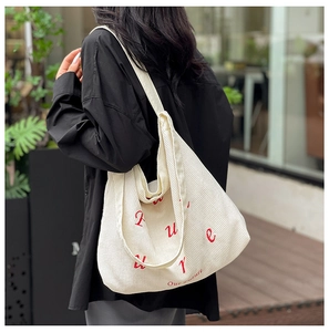 Macro del tessuto in velluto a coste bianco e scritte rosse ricamate su borsa tote
