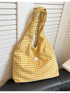 Large yellow and white checkered tote bag with a 'good' patch by white shutters