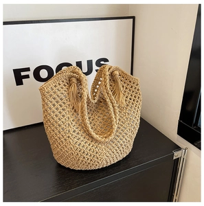Détail d'un sac à main en paille tissée avec motif ajouré et pompon décoratif