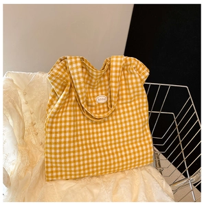 Detailed close-up of yellow checkered canvas tote bag with a white 'good' logo patch