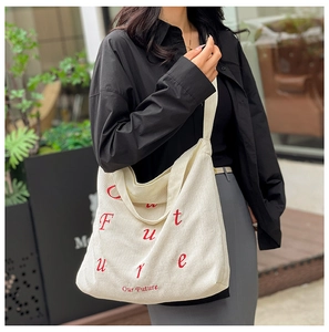 Dettaglio della borsa tote in velluto a coste bianco sporco con ricamo rosso 'Our Future'