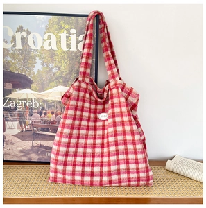 Detail of red and white plaid tote bag featuring a leather patch with good text