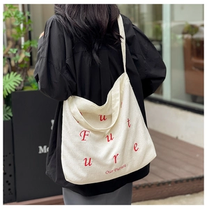 Dettaglio della borsa tote in velluto a coste beige con ricamo rosso e trama a coste