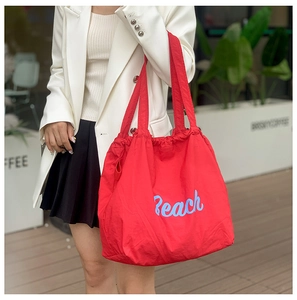 Detalle del bolso tote de nailon rojo con estampado Beach y cierre de cordón
