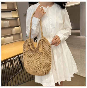 Detail of woven khaki straw bag showing mesh knit texture and matching tassel charms