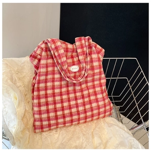 Macro detail of red and beige checkered knit tote bag with a good emblem in basket