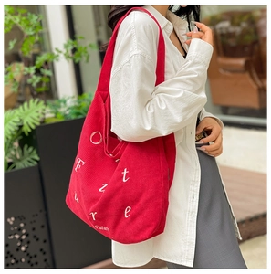 Texture dettagliata della borsa tote in velluto a coste rosso con stampa di lettere