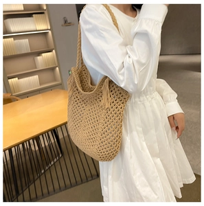 Détail d'un sac cabas en paille tissé à la main avec pompon décoratif et texture tressée