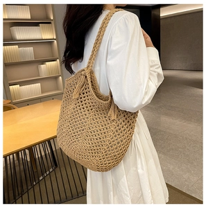 Detail of khaki woven tote bag with hollow out design and stylish tassel ornament