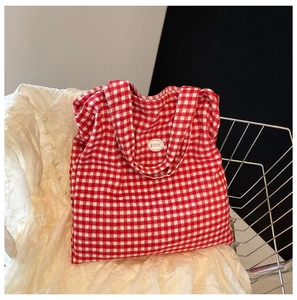 Detail view of red and white checkered tote bag with a white Good label on the front