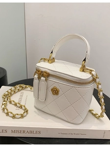 Mini bolso cubo acolchado blanco con cadena dorada y detalle de camelia en libros