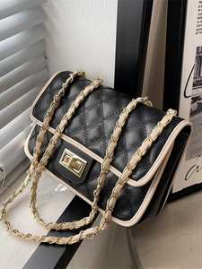 Borsa a tracolla trapuntata nera con bordo beige e catena dorata in studio fotografico