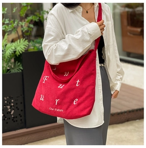 Dettaglio della borsa tote in velluto rosso con trama verticale e stampa di lettere Future