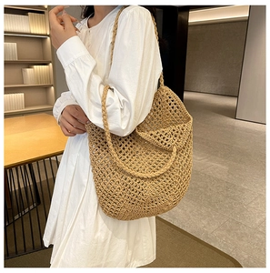 Detail of a beige woven straw shoulder bag with crochet hollow design and thick strap