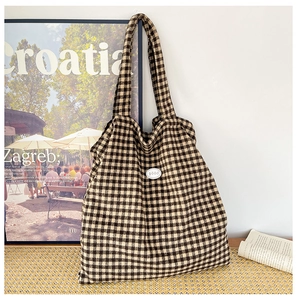 Detail of checkered canvas tote bag with oval good logo and vintage brown patterns