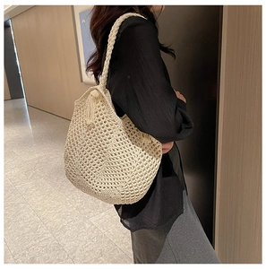 Détail d'un sac cabas tissé à la main blanc cassé avec maille épaisse et pompons latéraux
