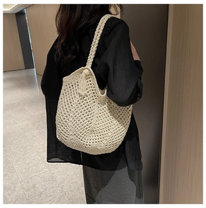 Close-up of cream hollow woven shoulder bag with stylish fringe detail and honeycomb texture