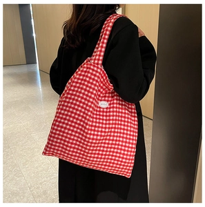 Detail of red and white gingham tote bag with a circular 'good' patch on a shoulder strap