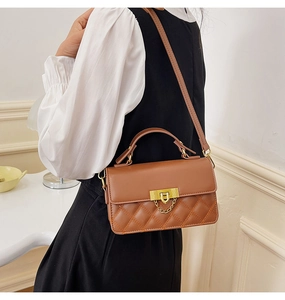 Detailansicht braune gesteppte Lederhandtasche mit Goldbeschlägen an Model