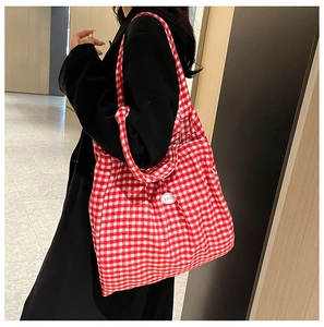 Close-up of red and white checkered fabric tote bag with side brand patch and handle