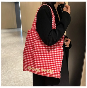 Detail of red and white checkered tote bag with yellow sleep well text on shoulder