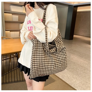 Brown and cream checkered tote bag shown worn by a model in a minimalist lifestyle setting