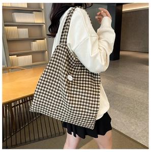 Close-up of checkered tote bag with a white 'good' emblem and woven texture