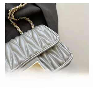 Detailed macro view of silver quilted chain bag with elegant gold twist lock hardware