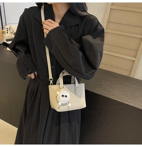 Close-up of contrast leather tote with lychee texture and plush monster bag charm
