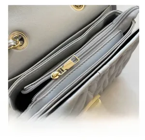 Macro view of silver quilted leather bag showing smooth gold zipper and multi-layer interior