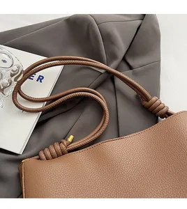 Close-up of brown lychee grain leather tote with knotted cylindrical shoulder strap details