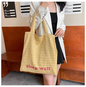 Close-up of yellow and white checkered tote bag featuring a red sleep well print