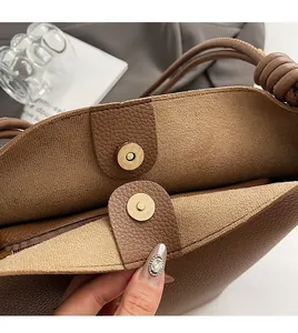 Detail of magnetic snap closure and suede lining on the brown leather bucket bag