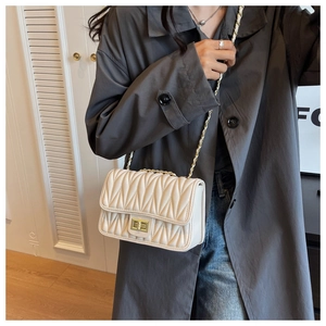 Close-up of beige quilted crossbody bag with matelassé texture and gold twist lock