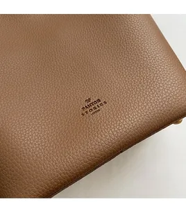 Close-up of brown pebbled leather texture featuring embossed logo on a bucket tote bag