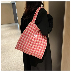 Detail of pink plaid tote bag with letter patch on tweed fabric shown on shoulder