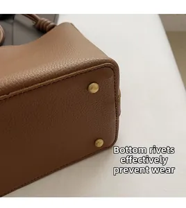 Detail view of golden bottom rivets on brown pebble leather bag to prevent wear