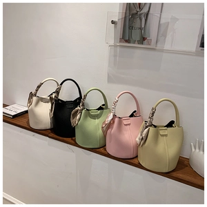 Niche bucket bags in various colors with woven handles and decorative silk scarves