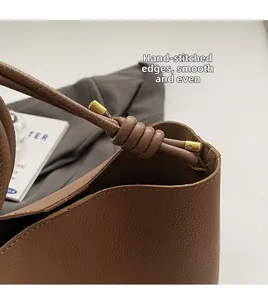 Close-up of a vintage brown tote bag showing precise stitching and gold buckle details