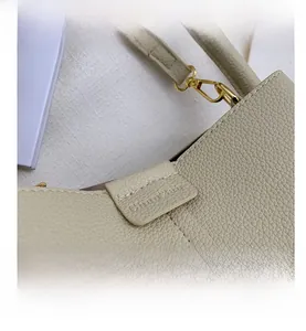 Macro view of beige lychee textured leather handbag with gold metal hardware details