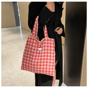 Pink and orange checkered tote bag with 'good' patch shown on model in modern setting