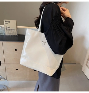 Detailed side view of white faux leather tote bag with silver bow hardware decoration