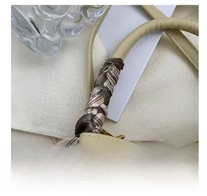 Detailed shot of cream lychee leather handbag handle wrapped in vintage print silk scarf