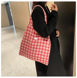 Detail shot of red plaid tote bag with good patch showing textured fabric and strap