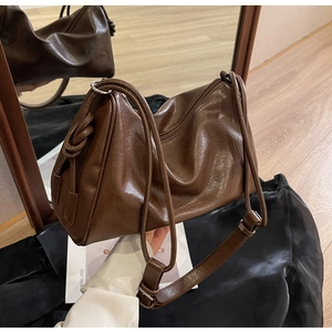 Detail of dark brown leather Boston bag showing side knot accents and wide shoulder strap