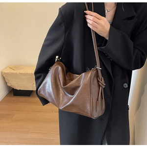 Detail of dark brown slouchy Boston bag with unique knot decoration on the shoulder strap