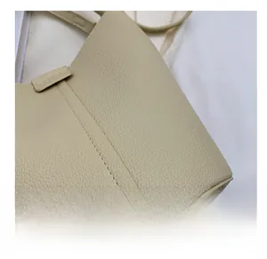 Close-up of beige litchi pattern leather texture and fine stitching on bucket bag