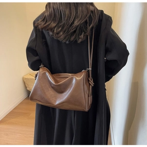 Brown vintage Boston bag featuring a side knot design and glossy leather finish