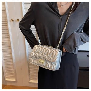 Detail of silver quilted chain bag with gold twist lock and metallic finish on shoulder
