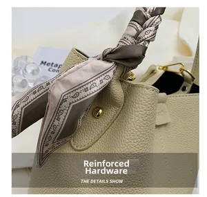 Detail of beige lychee leather bucket bag with gold hardware and paisley silk scarf